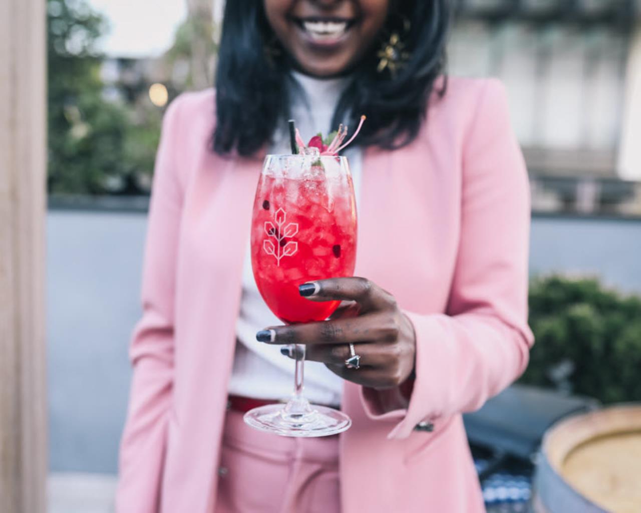 Girl dressed in pink holding a rose crush cocktail from Hadiqua