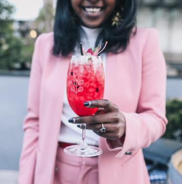 Girl dressed in pink holding a rose crush cocktail from Hadiqua