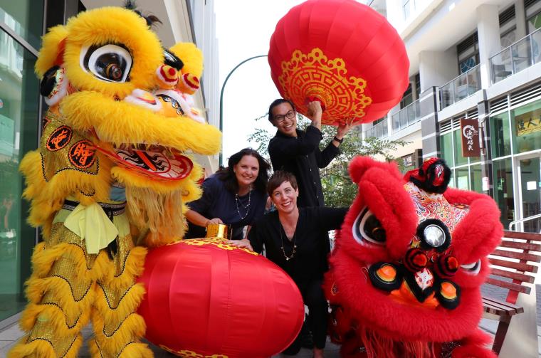 People celebrating Lunar New Year with red lanterns and lion dancers