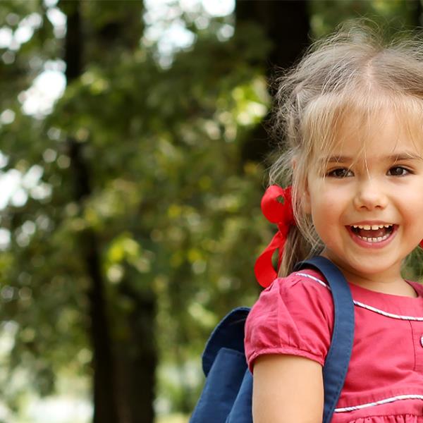 Smiling preschool girl with backpack. 
