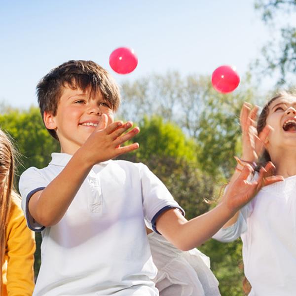Children juggling outside in a park.