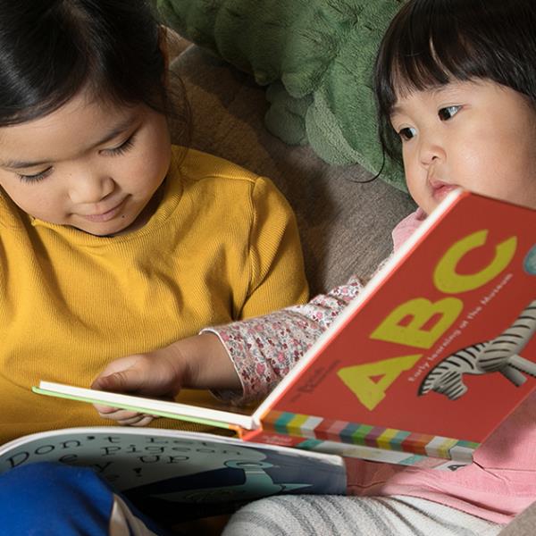 Two girls reading picture books at the Library