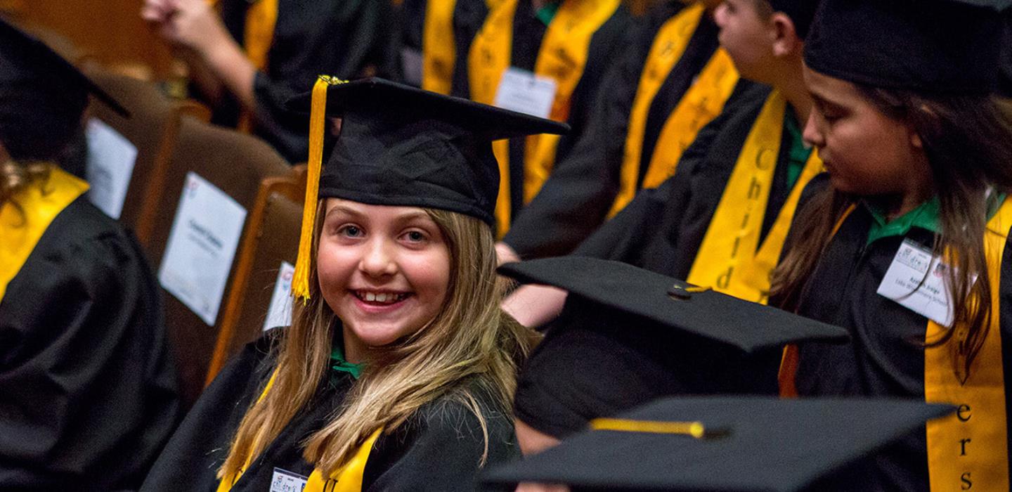 Children in university graduation gowns