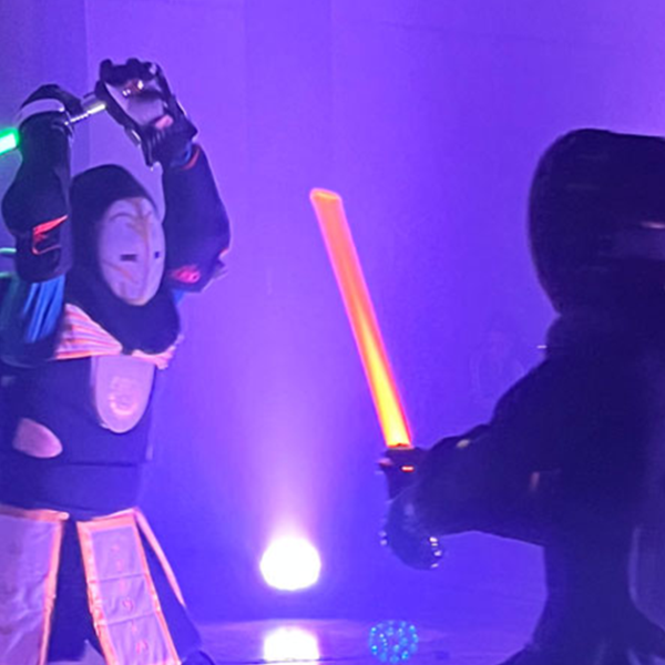 Two people in costume dueling with Lightsabers 