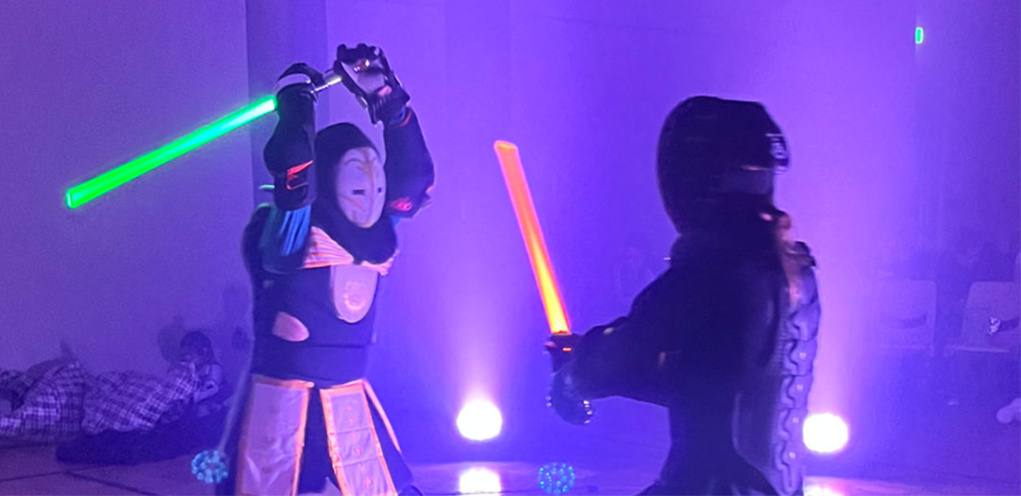 Two people in costume dueling with Lightsabers 