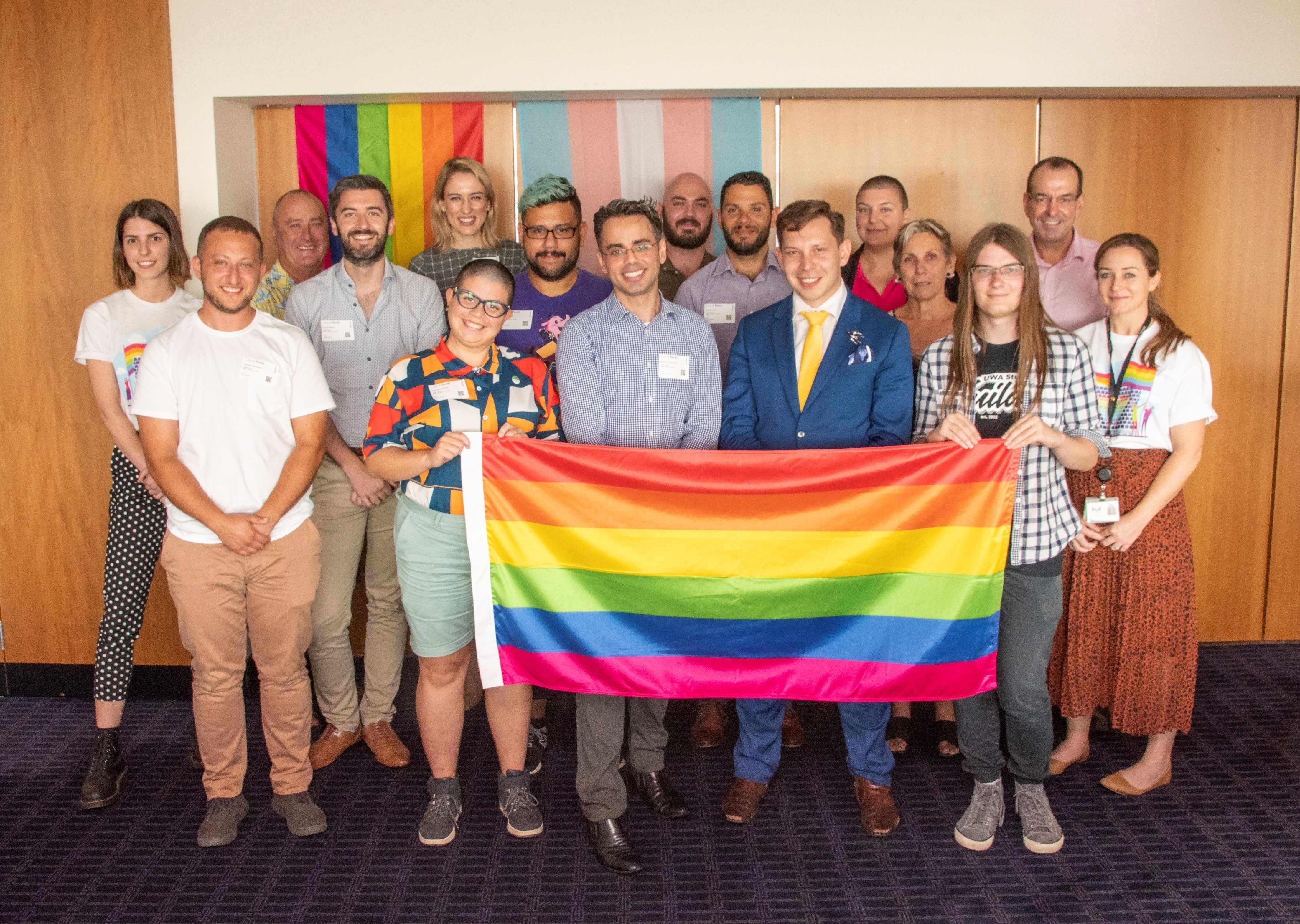 LGBTQIA Advisory Group in front of Pride and trans flags