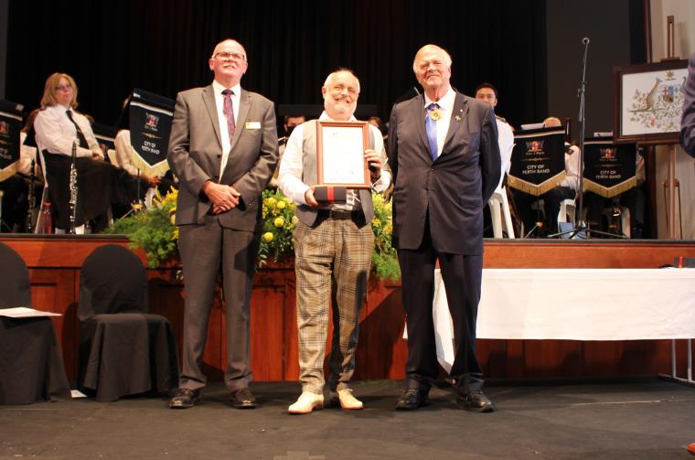 Tibor Meszaros holding a certificate and standing in between Cmr Andrew Hammond and Kim Beazley.