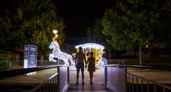Two people walking towards a lit up horse and carriage at part of the Christmas lights trail activation