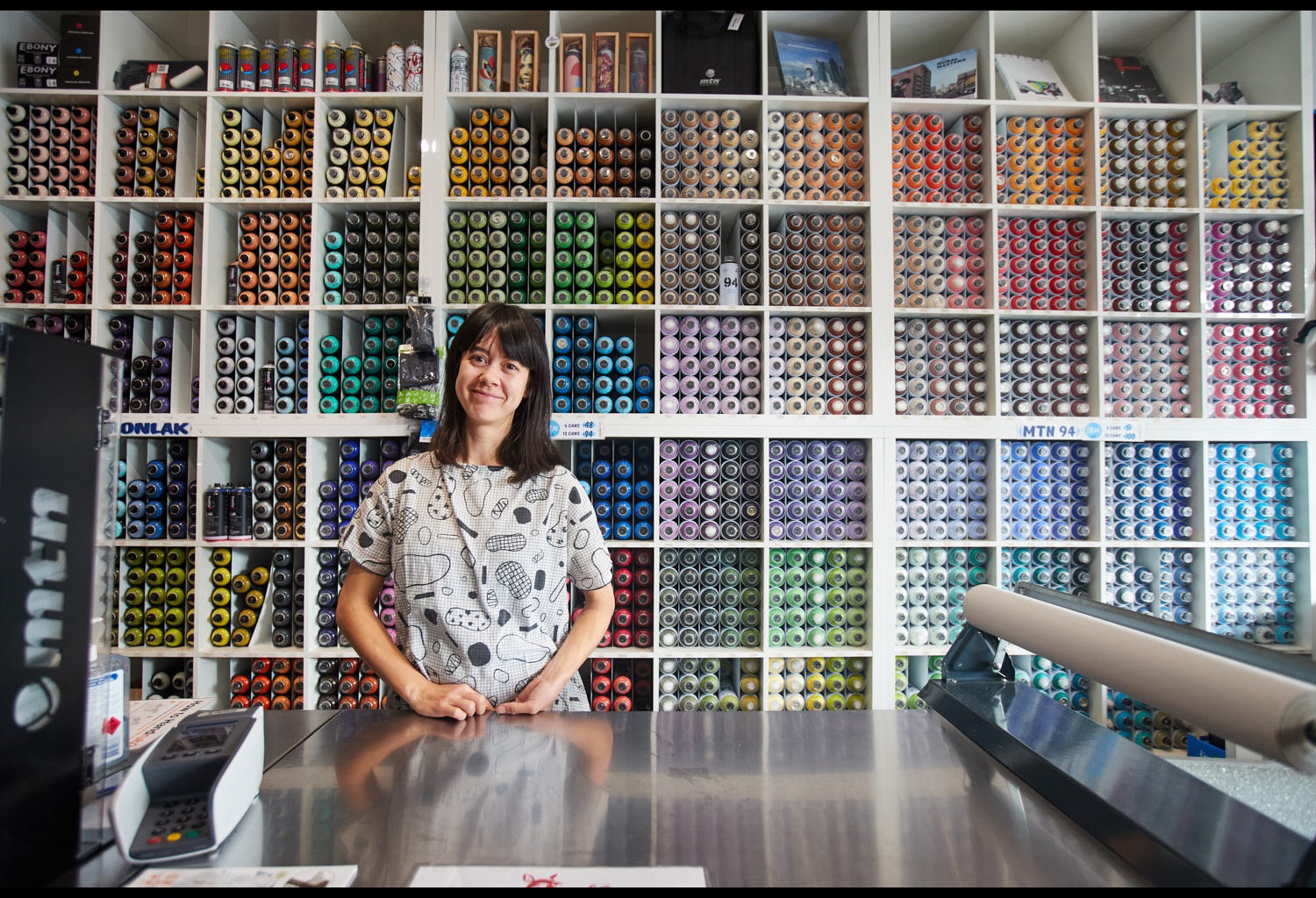 The Butcher Shop sales assistant stands in front of wall of paint