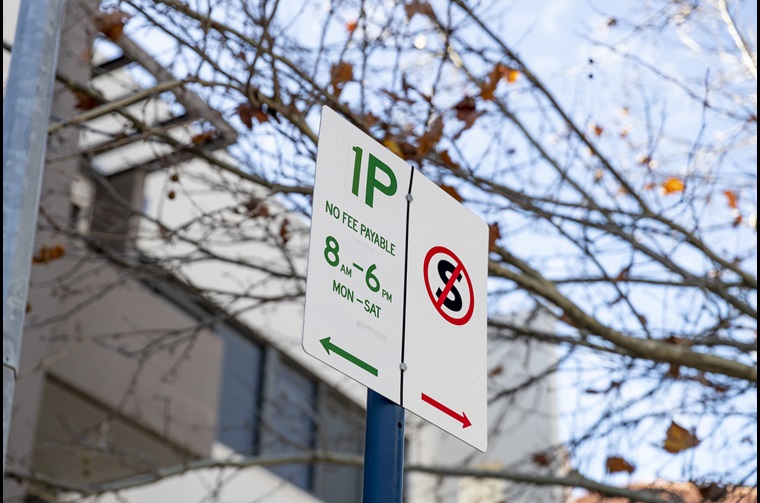 Parking sign that says '1P no fee payable' with tree branch in background
