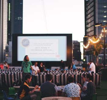 People eating in front of rooftop movie at sunset