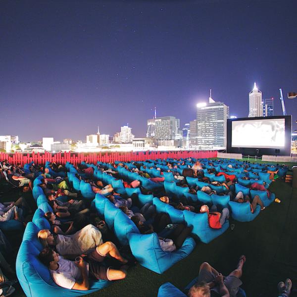 View of audience watching movie on rooftop with City in background