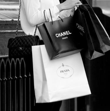 Person holding Chanel and Prada shopping bags