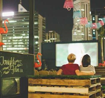 Couple watching a rooftop movie with city in background
