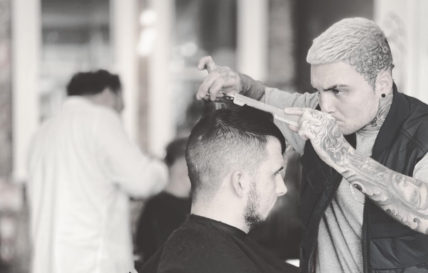 Black and white photo of barber doing man's hair