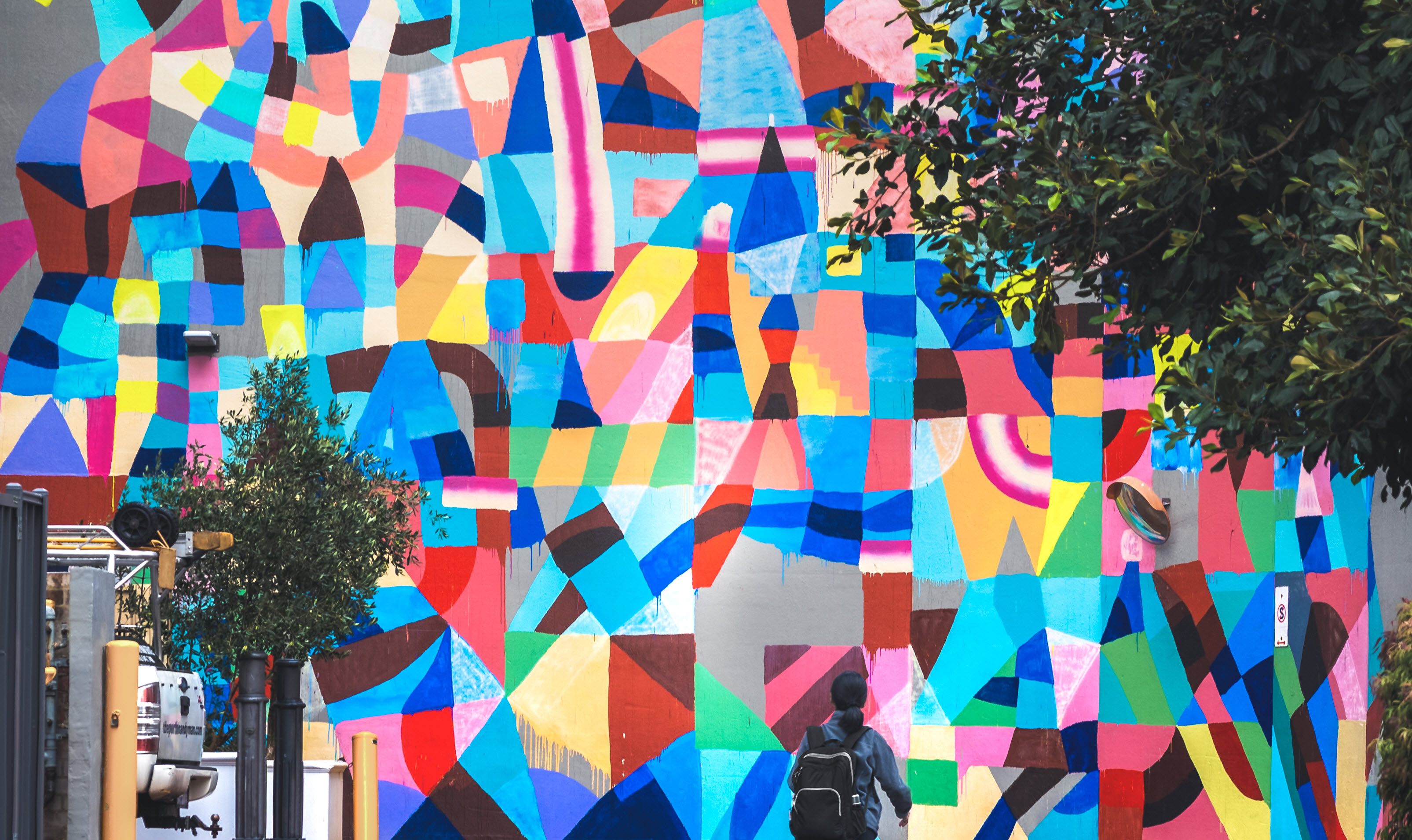 Person standing in front of colourful mural