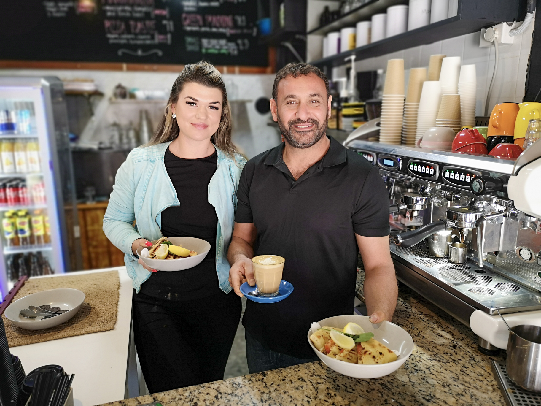 Lady and man holding plates of food in a cafe